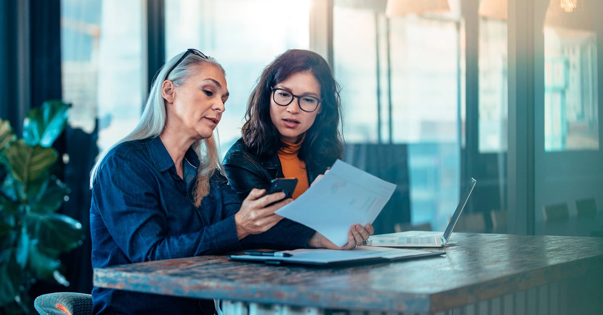 kaksi ihmistä katsoo puhelinta