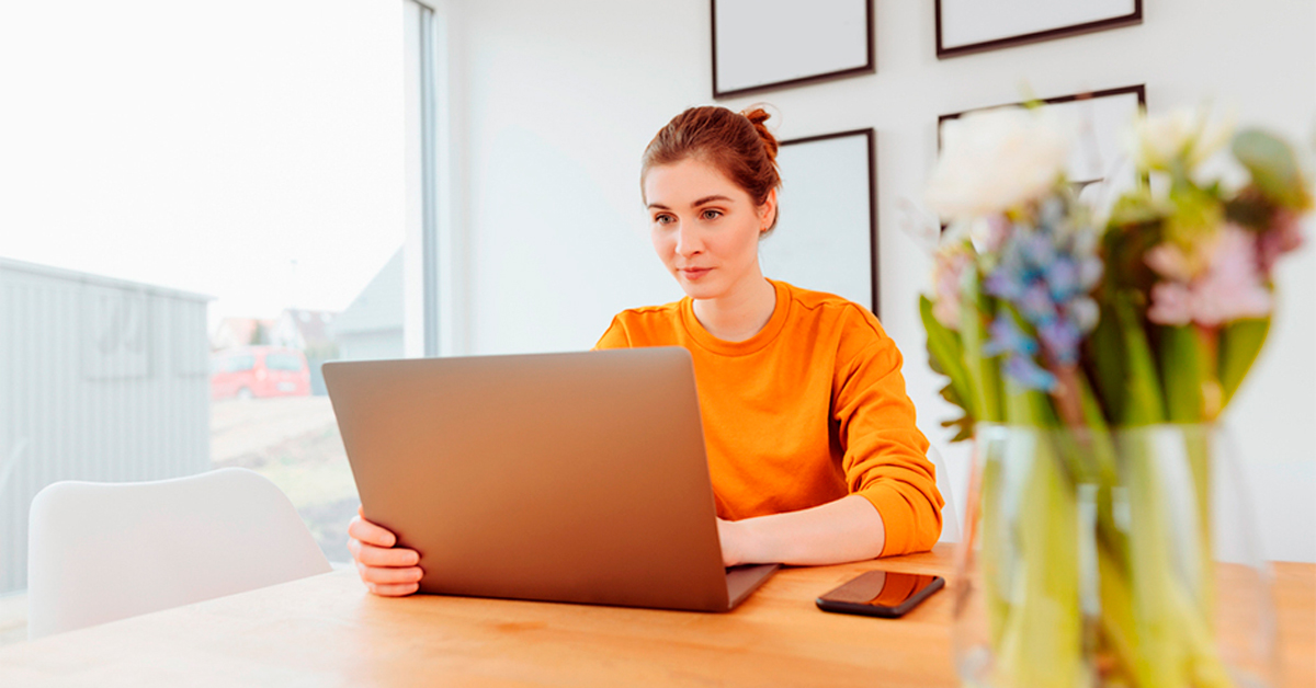 Nainen käyttää tietokonetta pöydän ääressä